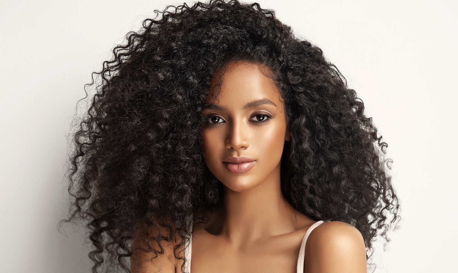 Woman with voluminous curly hair on a plain background