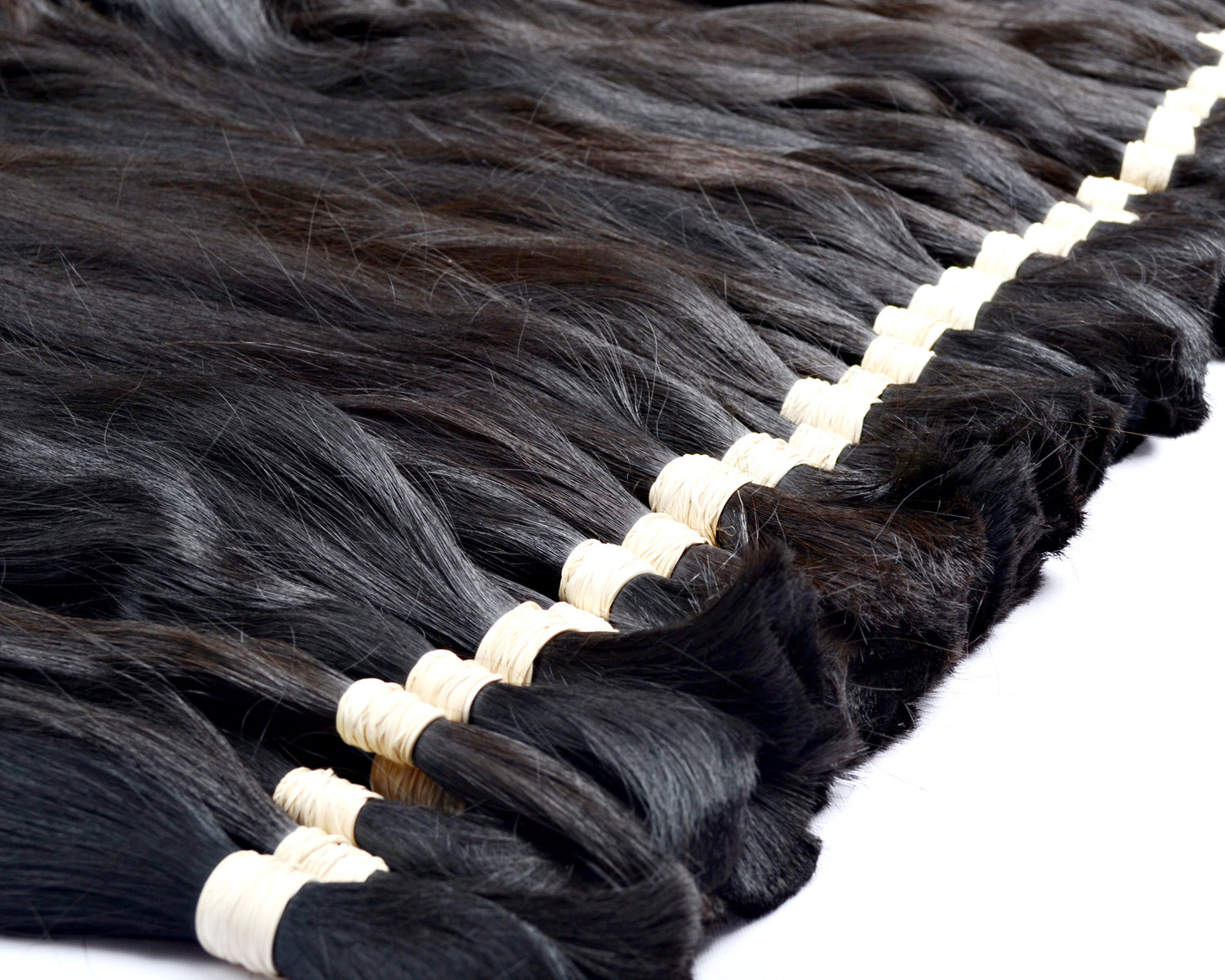 Bundle of black hair extensions with white bands on a white background